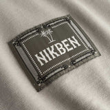 Closeup view of green Nikben patch logo on beige T-shirt