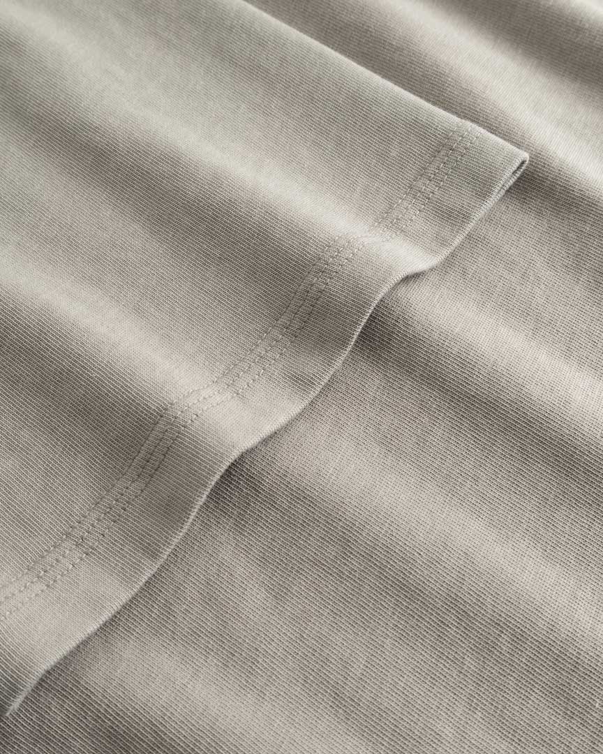 Closeup view of arm stitchings on beige T-shirt