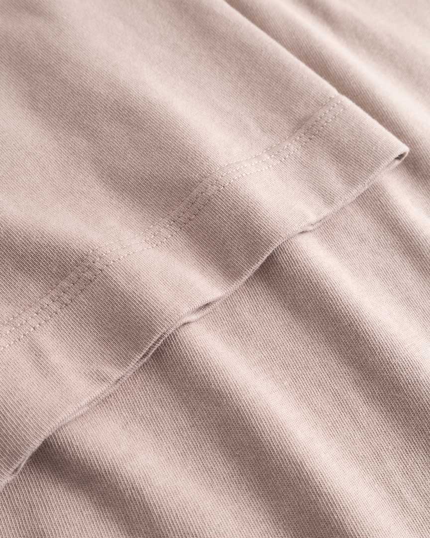 Closeup view of arm stitchings on beige T-shirt