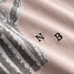 Closeup view of white embroidered NB initials next to cactus print on beige T-shirt