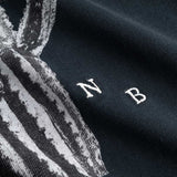 Closeup view of white embroidered NB initials next to cactus print on black T-shirt