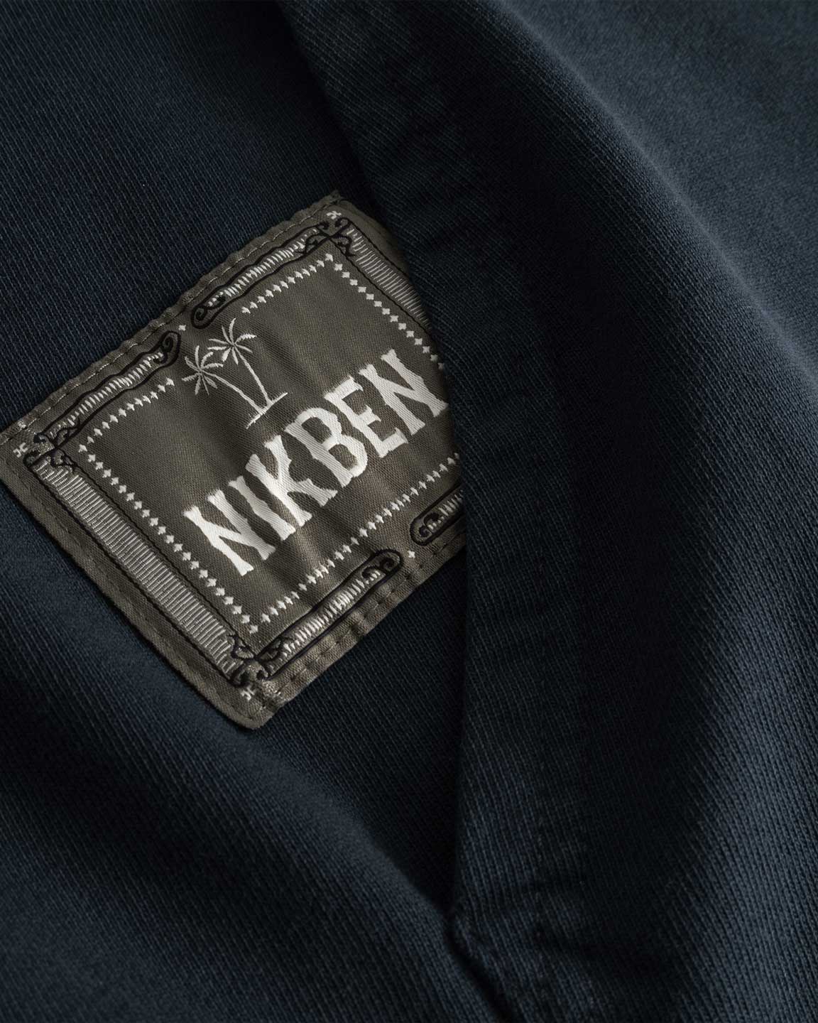Closeup view of green Nikben patch logo next to left pocket on black hoodie 