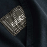 Closeup view of green Nikben patch logo next to left pocket on black hoodie 