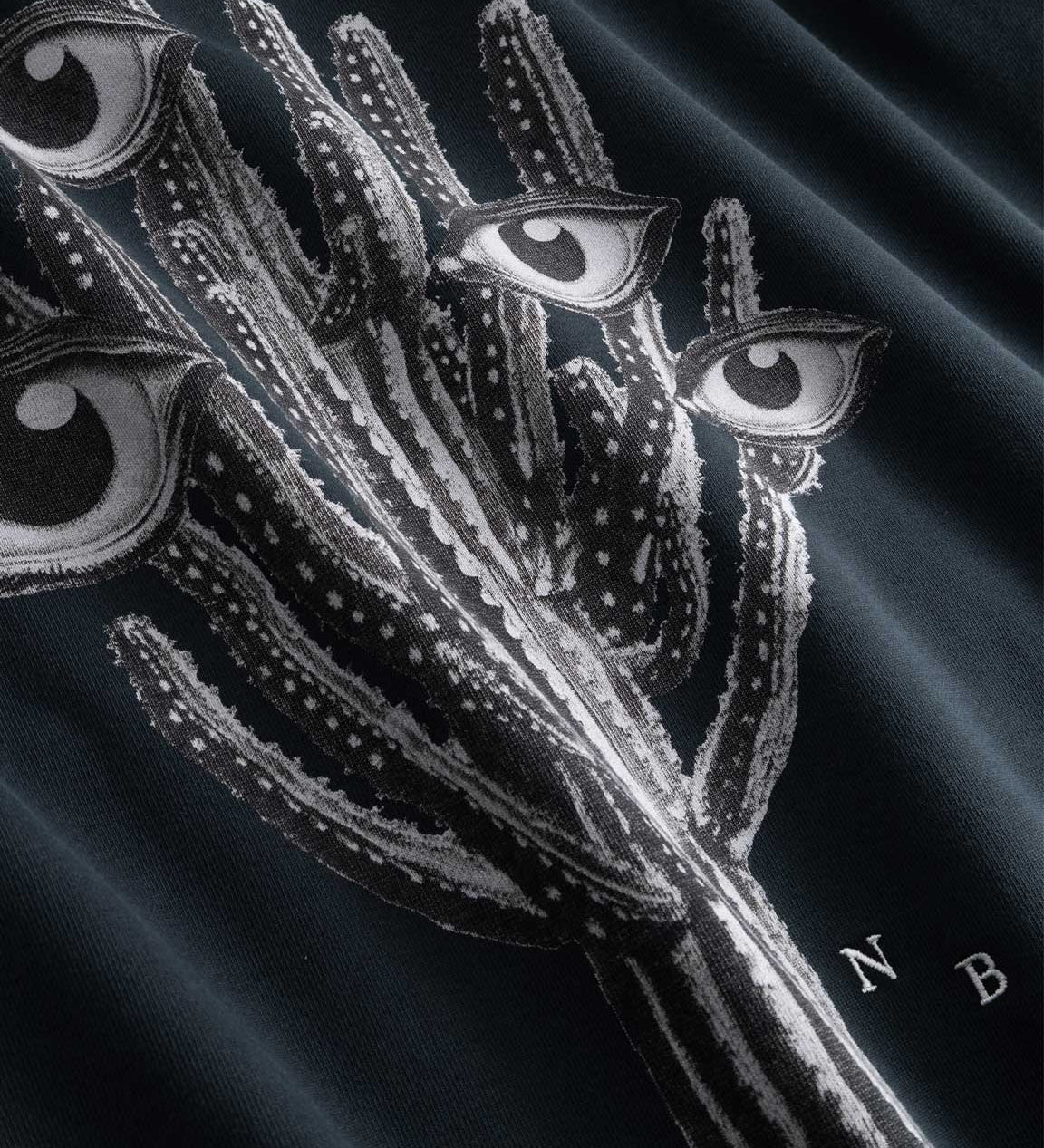 Closeup view of black and white cactus print and NB embroidered initials on black hoodie