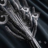 Closeup view of black and white cactus print and NB embroidered initials on black hoodie