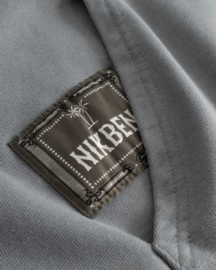Closeup view of green Nikben patch logo next to left pocket on grey hoodie