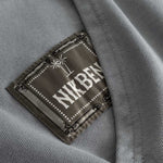 Closeup view of green Nikben patch logo next to left pocket on grey hoodie