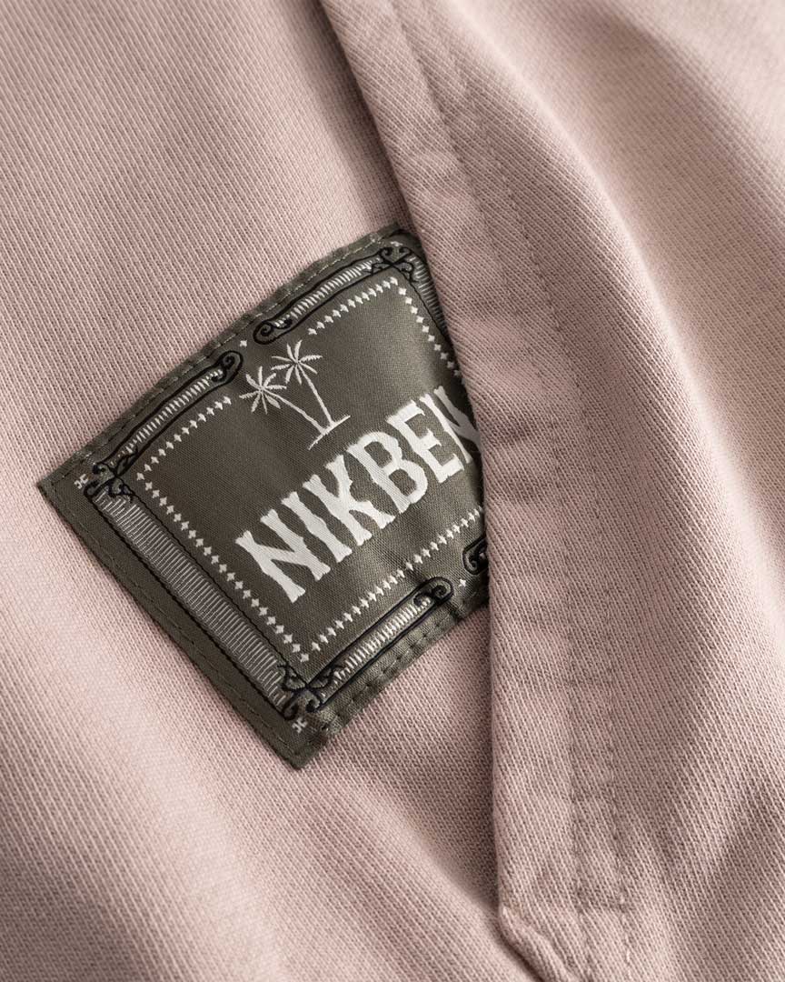 Closeup view of green Nikben patch logo next to left pocket on brown hoodie 