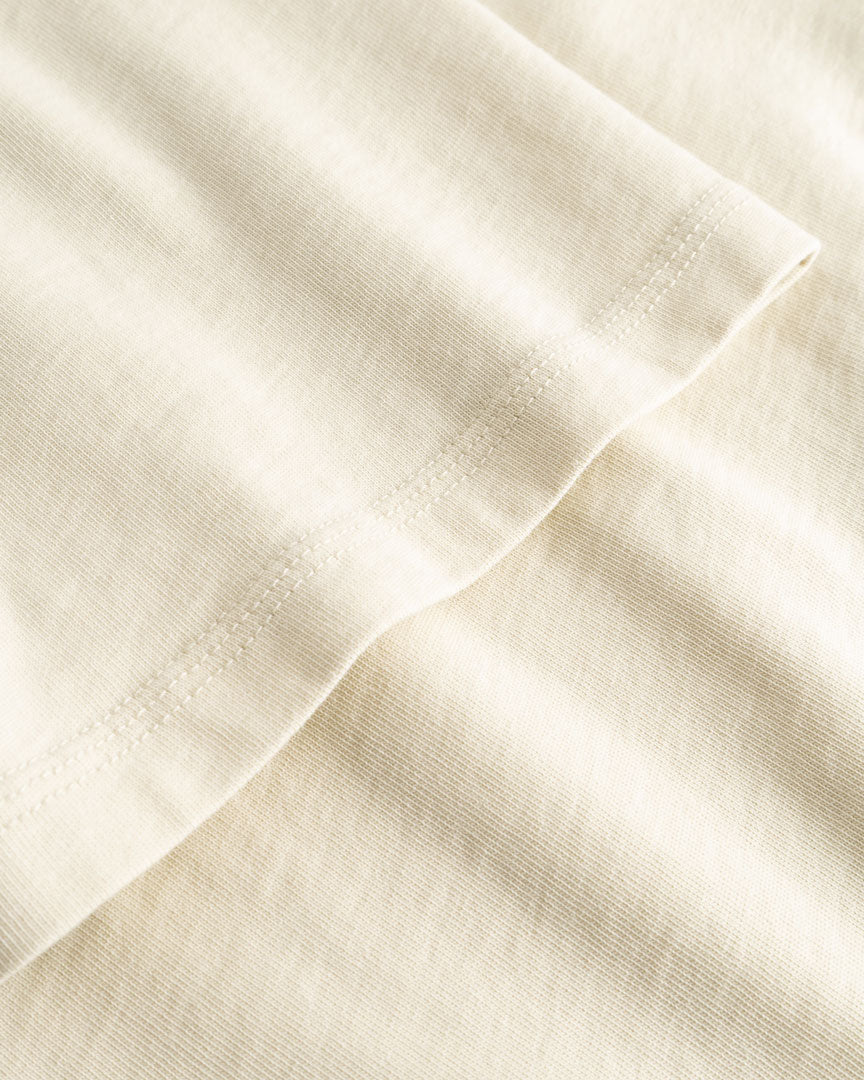 Closeup view of arm stitchings on beige T-shirt