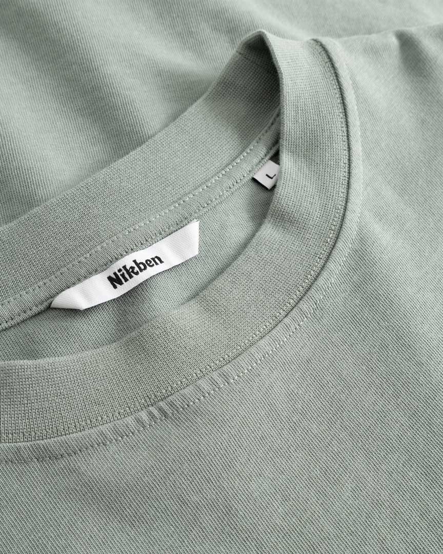 Closeup view of Nikben necklabel on green T-shirt