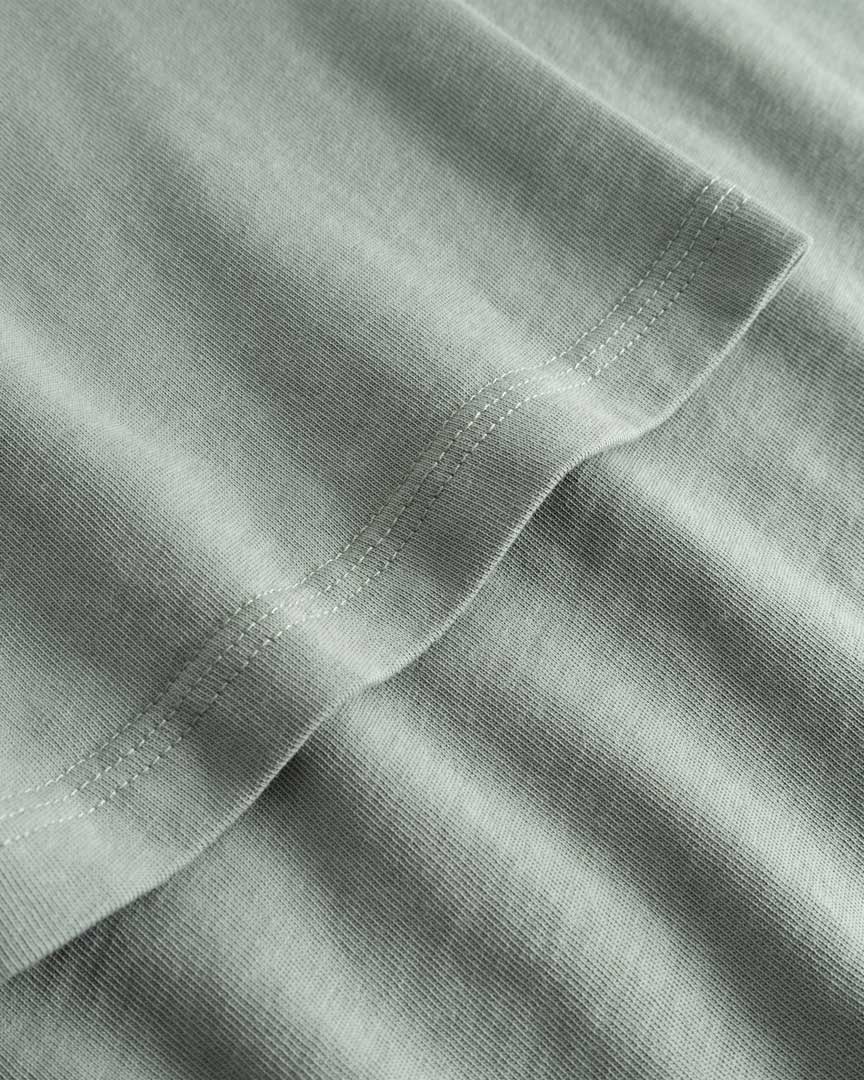 Closeup view of arm stitchings on green T-shirt