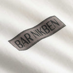 Closeup view of brown "BAR NIKBEN" logo on white T-shirt