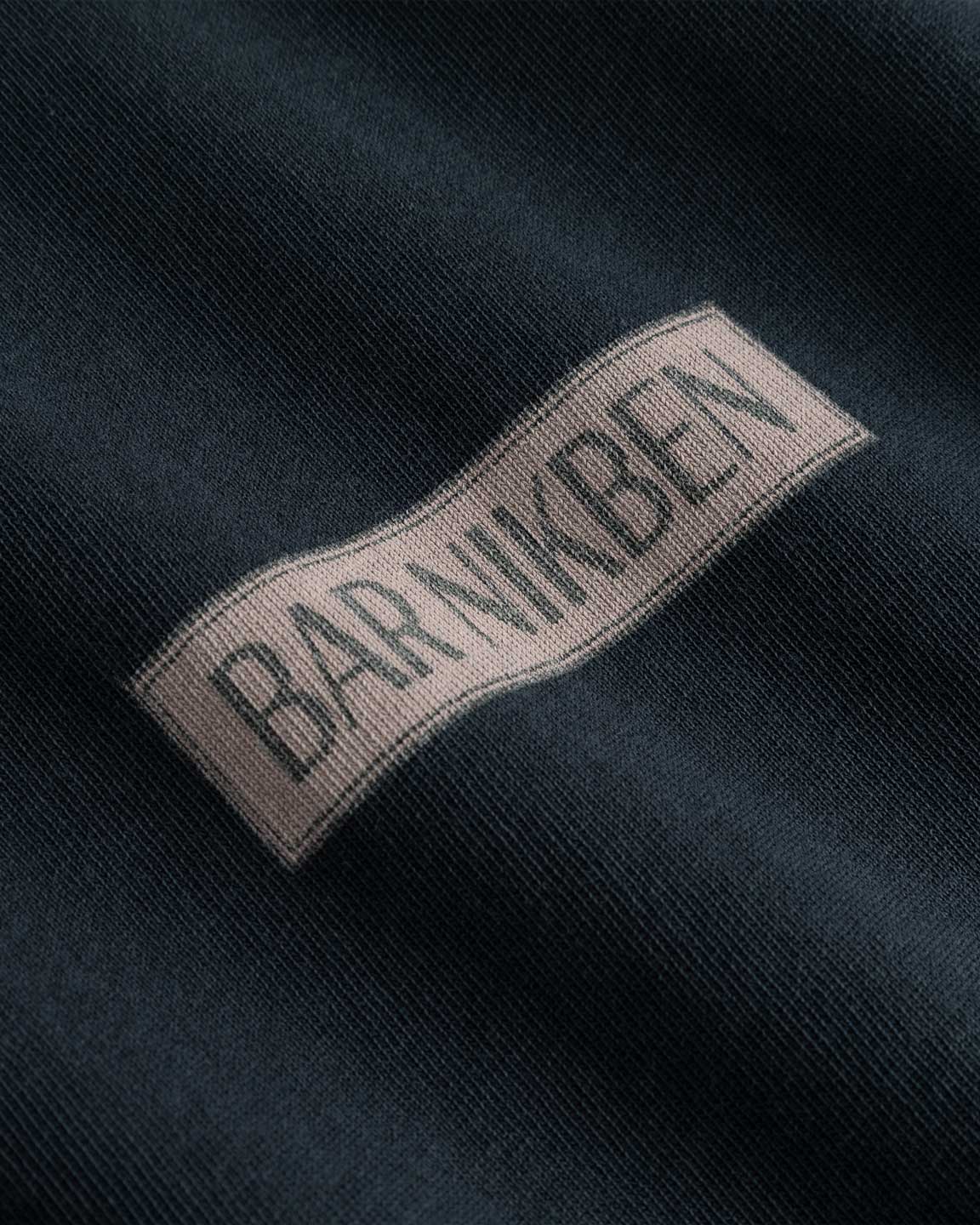 Closeup view of brown "BAR NIKBEN" logo on black T-shirt