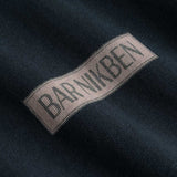 Closeup view of brown "BAR NIKBEN" logo on black T-shirt