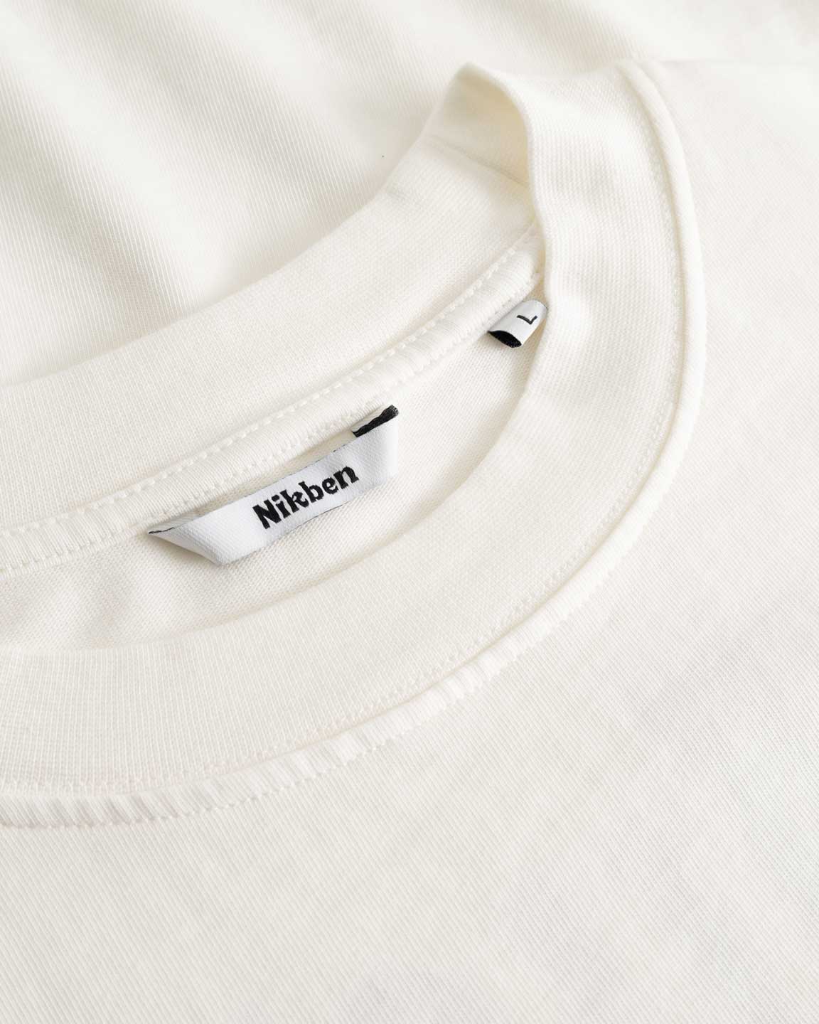 Closeup view of Nikben necklabel on white longsleeve T-shirt