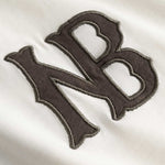 Closeup view of brown NB logo on white longsleeve T-shirt