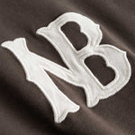 Closeup view of white NB logo on brown longsleeve T-shirt