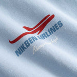 Closeup view of blue Nikben Airlines logo and red airplane print on light blue T-shirt