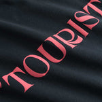 Closeup view of pink "TOURIST" print on black T-shirt