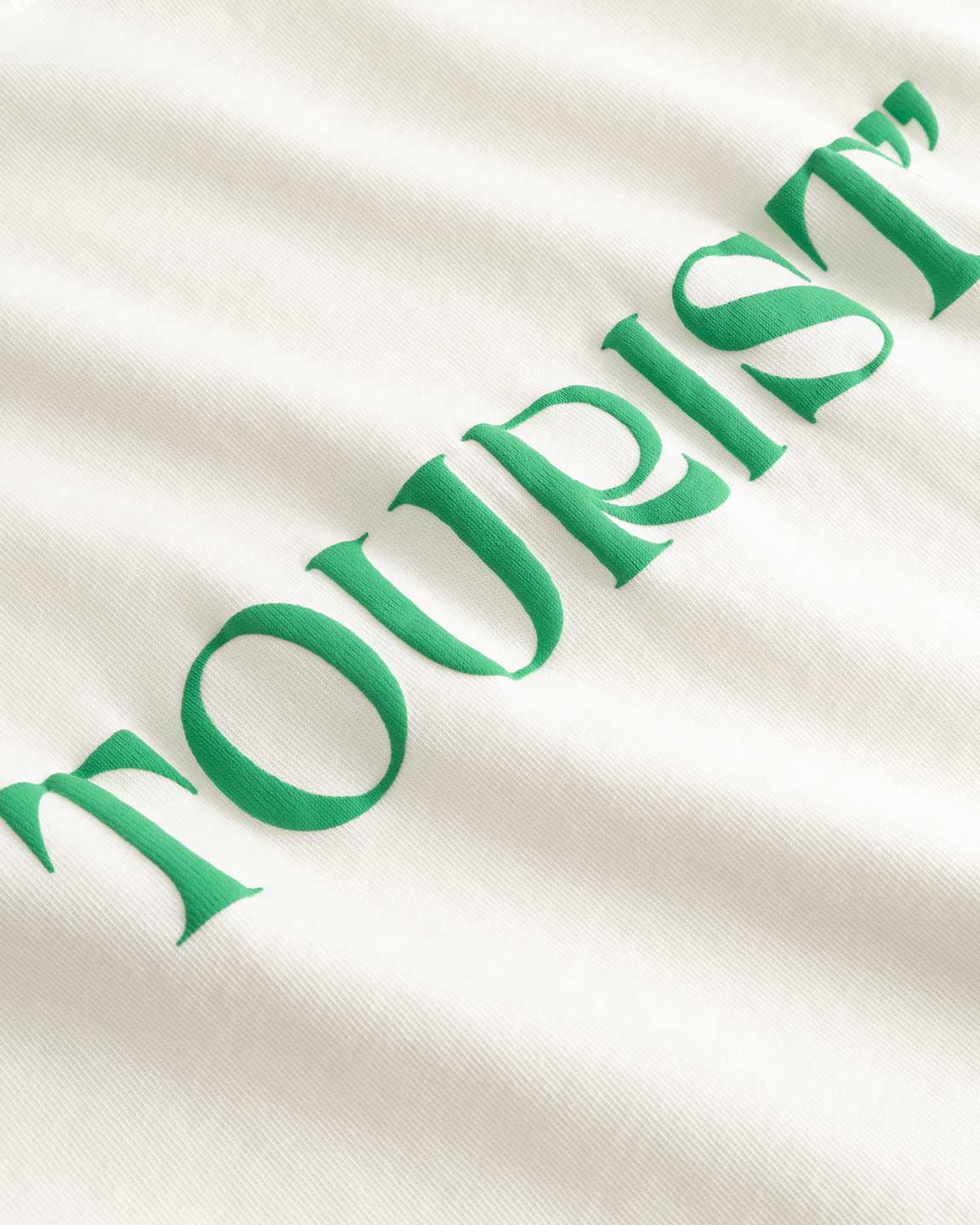 Closeup view of green "TOURIST" print on white T-shirt