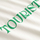 Closeup view of green "TOURIST" print on white T-shirt