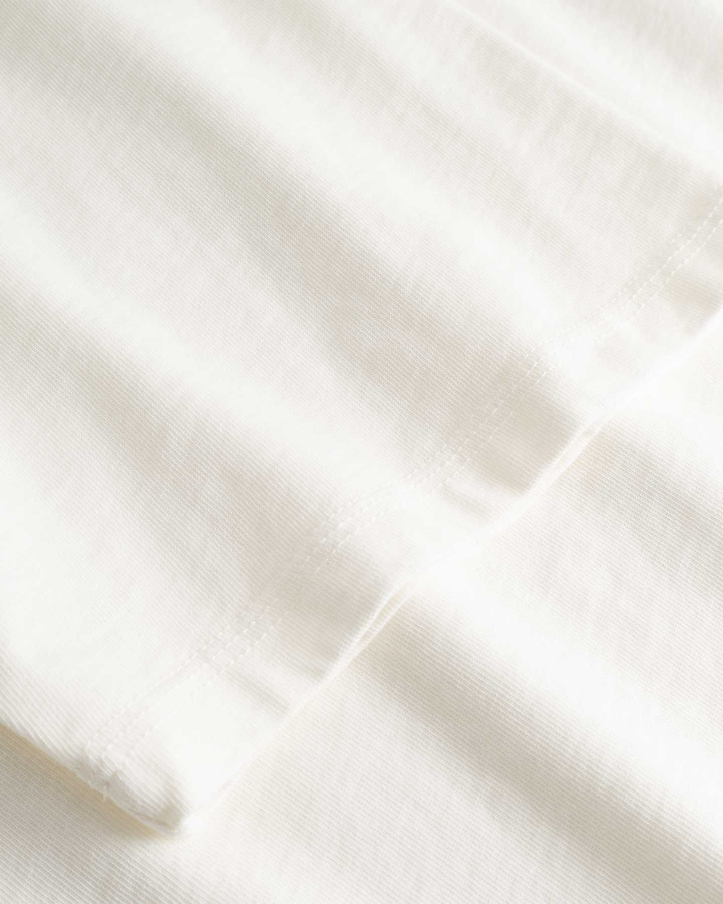 Closeup view of arm stitchings on white T-shirt