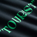 Closeup view of green "TOURIST" print on  black hoodie