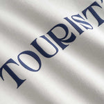Closeup view of blue "TOURIST" print on  gray hoodie