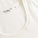 Closeup view of Nikben necklabel on white ribbed tank top