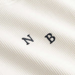Closeup view of black NB initials on white ribbed tank top