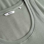 Closeup view of Nikben necklabel on green ribbed tank top