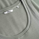 Closeup view of Nikben necklabel on green ribbed tank top
