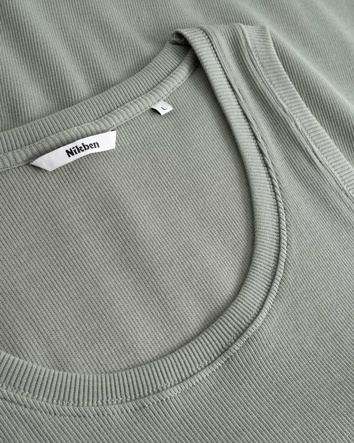 Closeup view of Nikben necklabel on green ribbed tank top