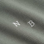 Closeup view of white NB initials on green ribbed tank top