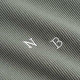 Closeup view of white NB initials on green ribbed tank top