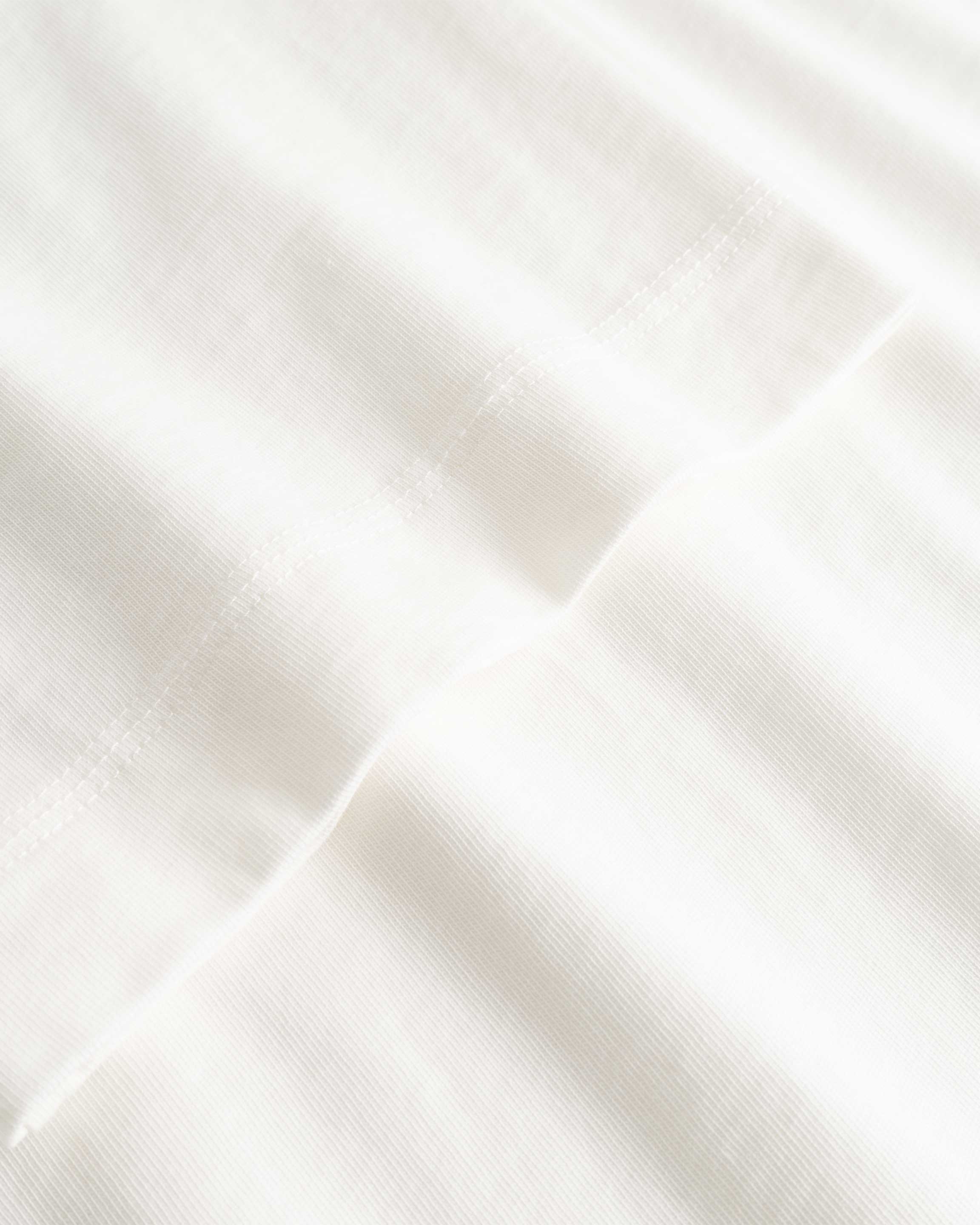 Closeup view of arm stitchings on white T-shirt