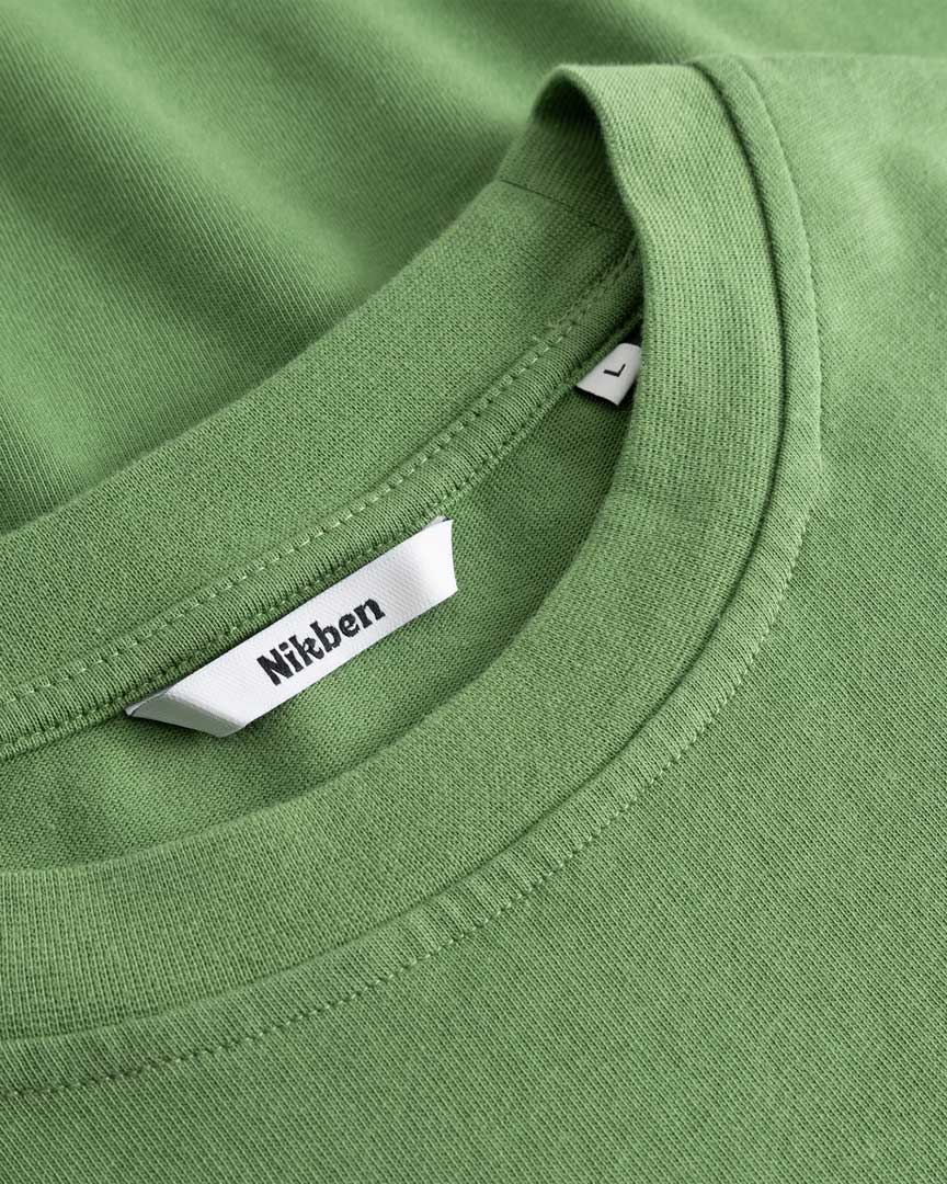 Closeup view of Nikben necklabel on green T-shirt