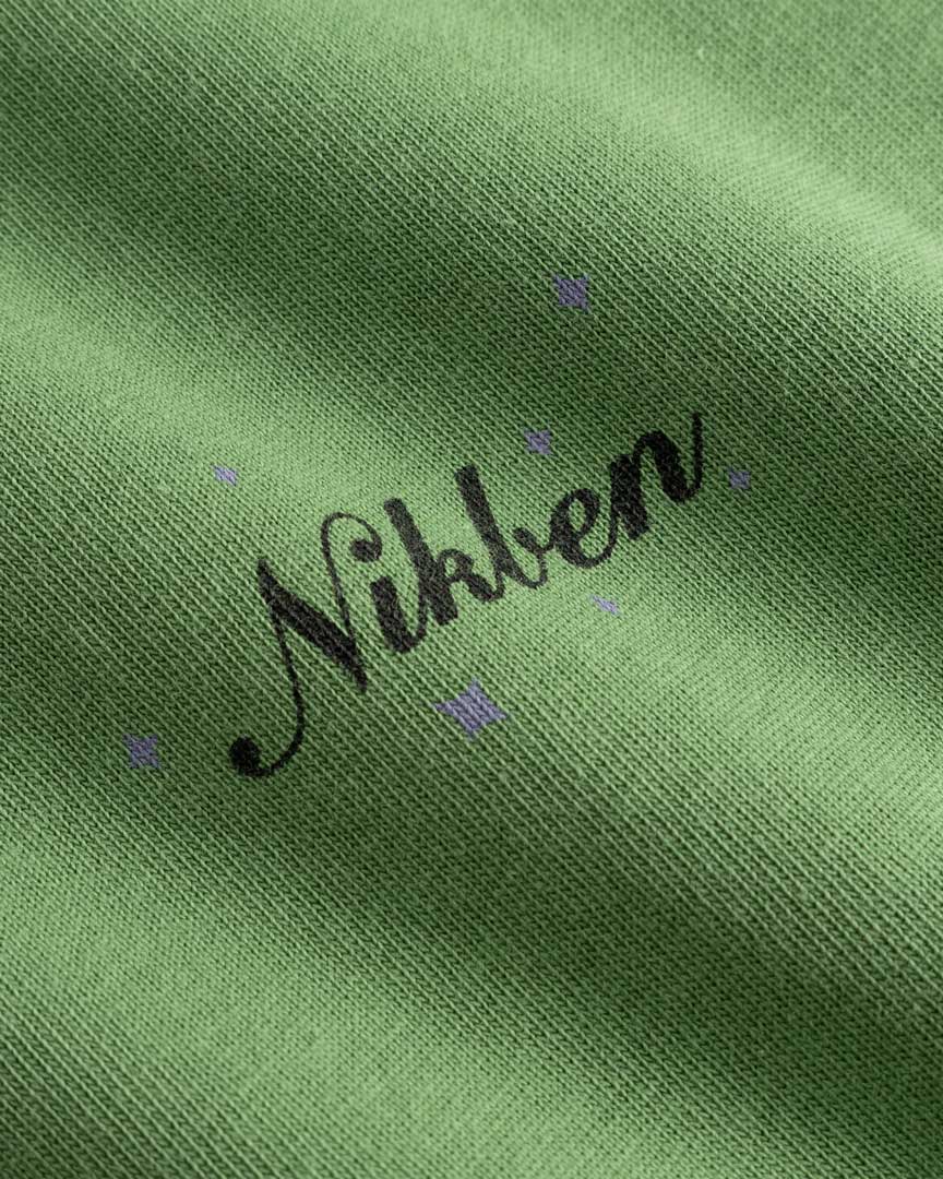 Closeup view of black Nikben logo on green T-shirt