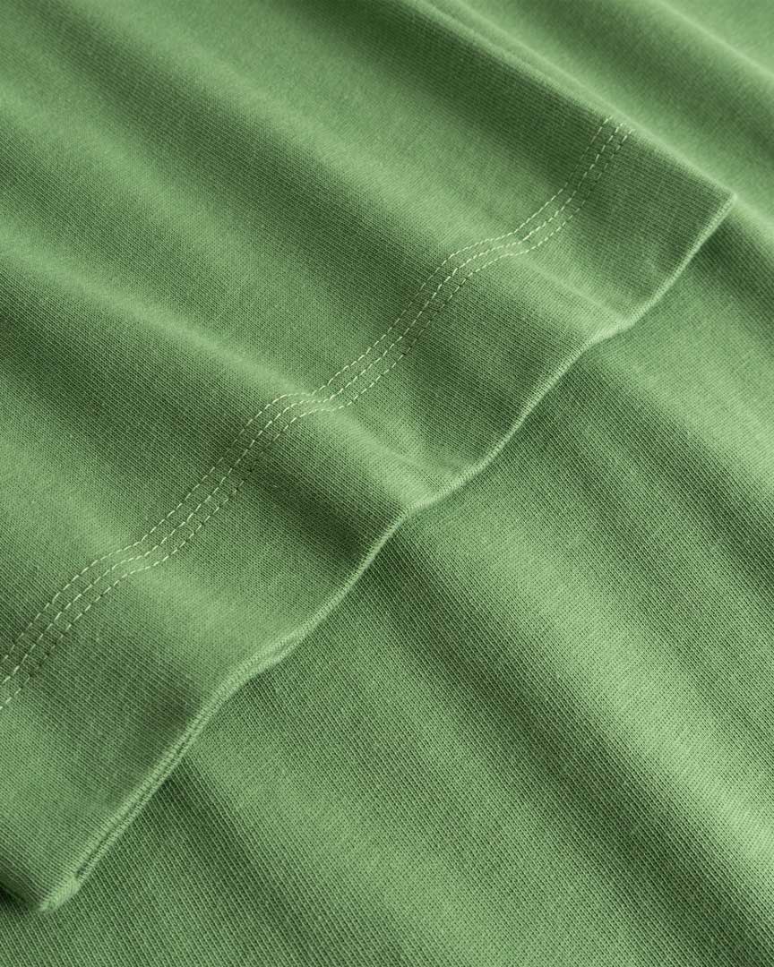 Closeup view of arm stitchings on green T-shirt