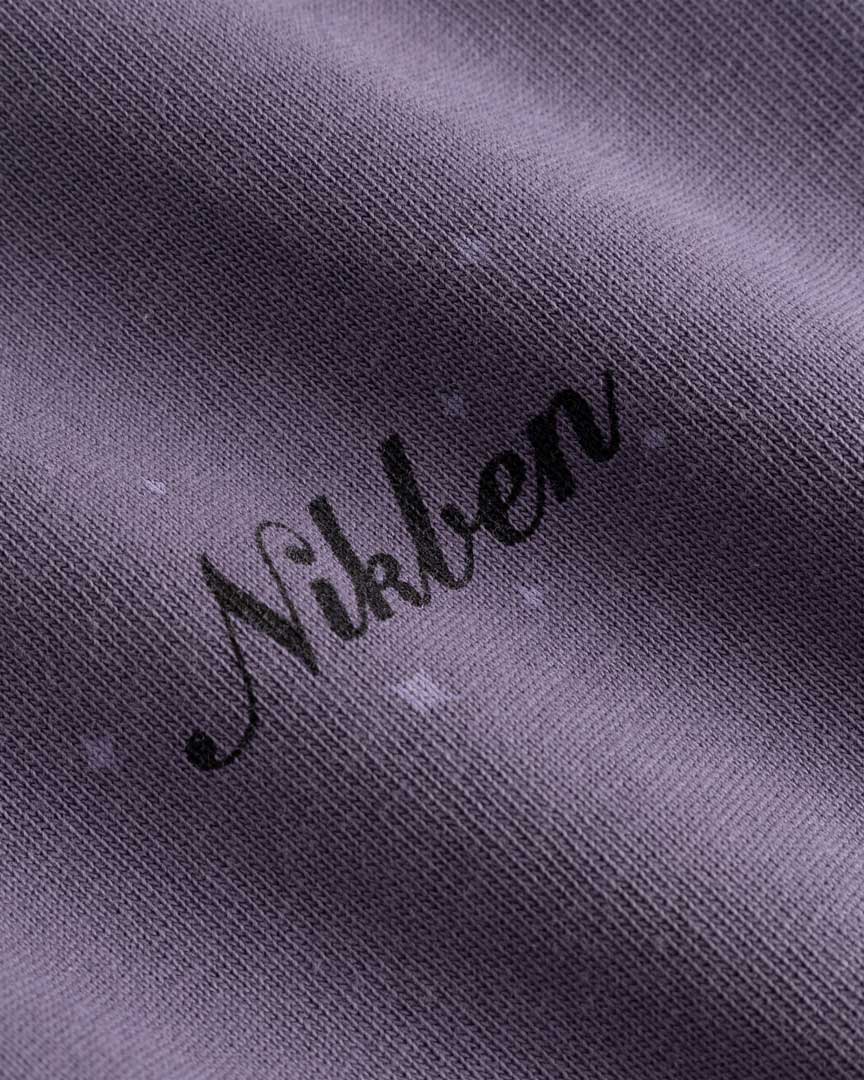 Closeup view of black Nikben logo on purple T-shirt