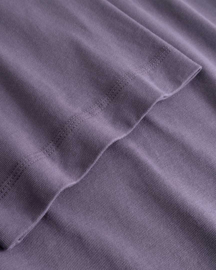 Closeup view of arm stitchings on purple T-shirt