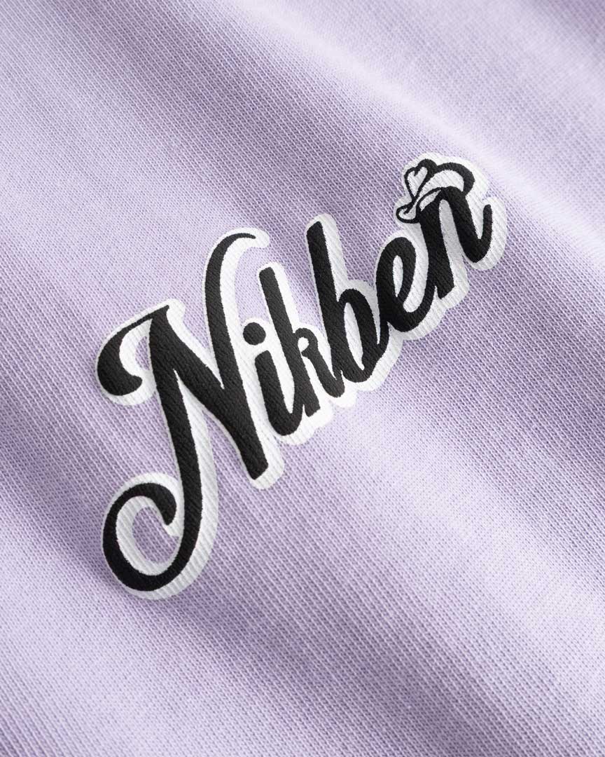 Closeup view of black and white Nikben logo on light purple T-shirt