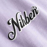 Closeup view of black and white Nikben logo on light purple T-shirt