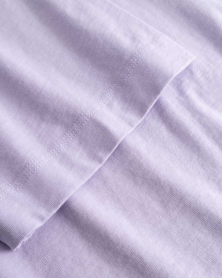 Closeup view of arm stitchings on light purple T-shirt