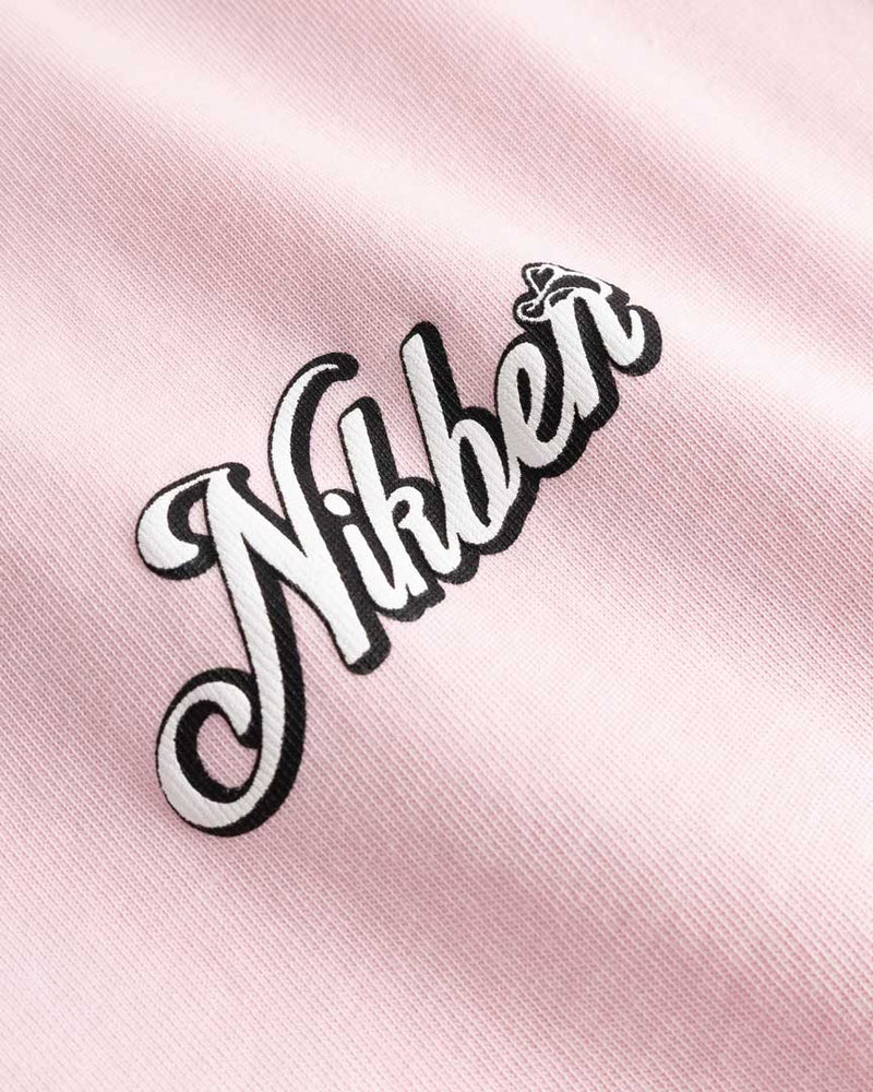 Closeup view of black and white Nikben logo on light pink T-shirt