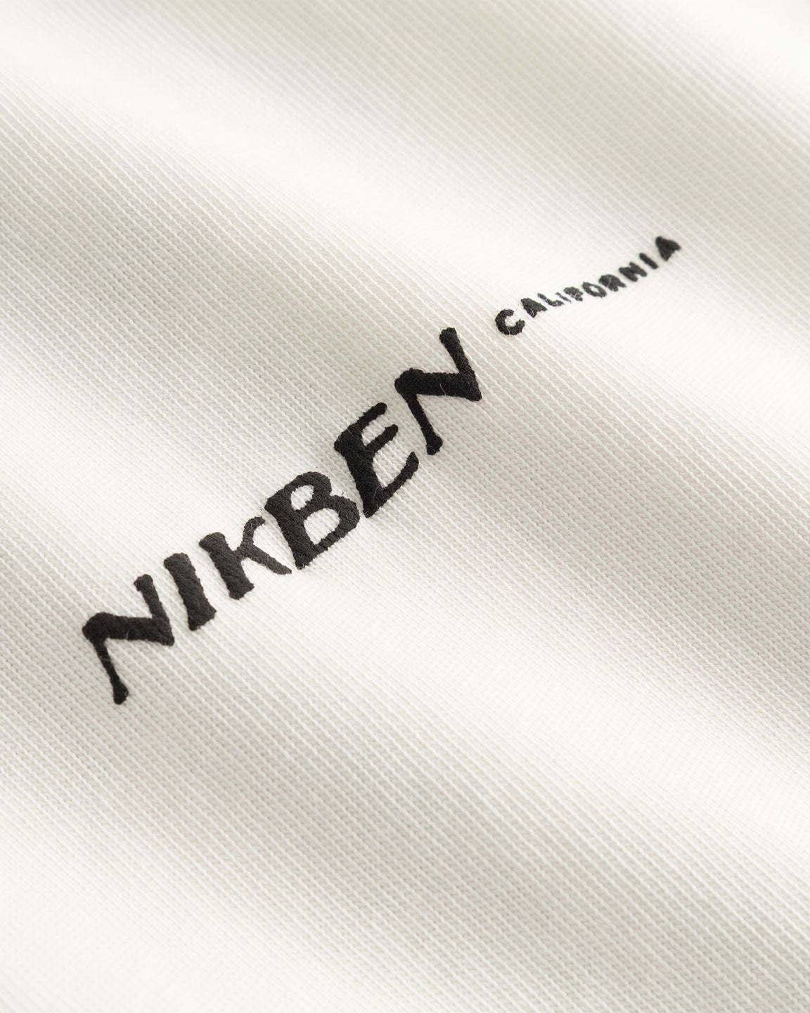 Closeup view of black "Nikben California" logo on white T-shirt