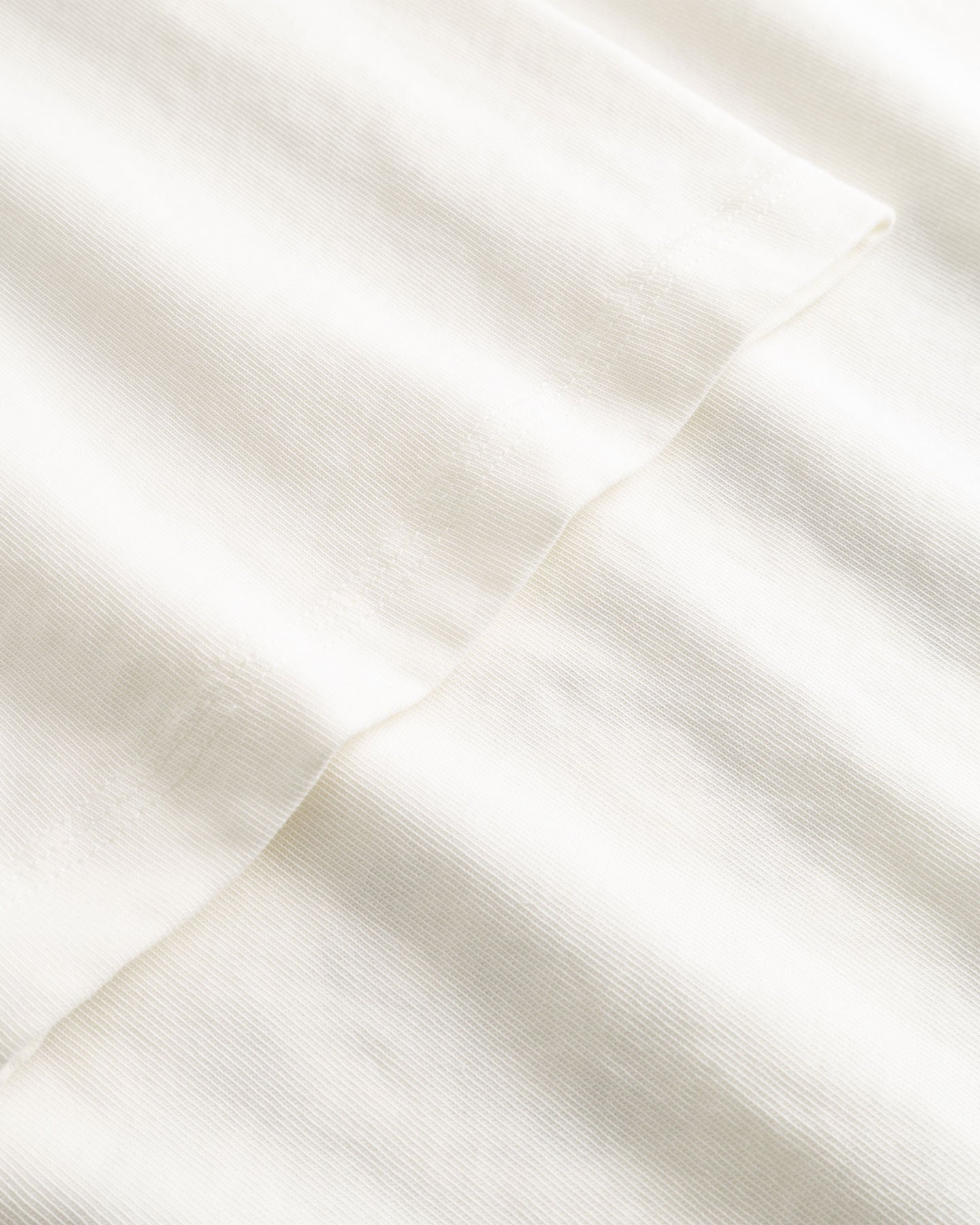Closeup view of arm stitchings on white T-shirt