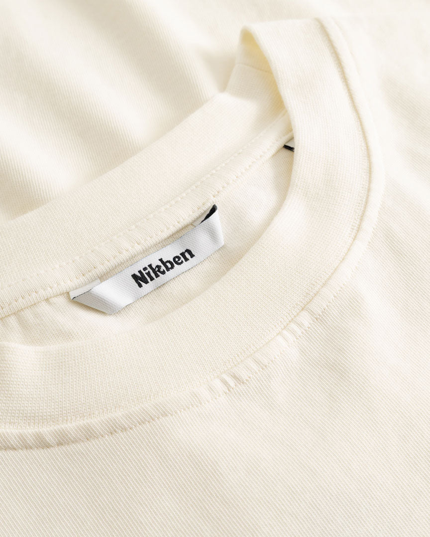 Closeup view of Nikben necklabel on cream colored T-shirt