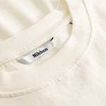Closeup view of Nikben necklabel on cream colored T-shirt