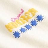 Closeup view of yellow, blue and pink Nikben logo on cream colored T-shirt